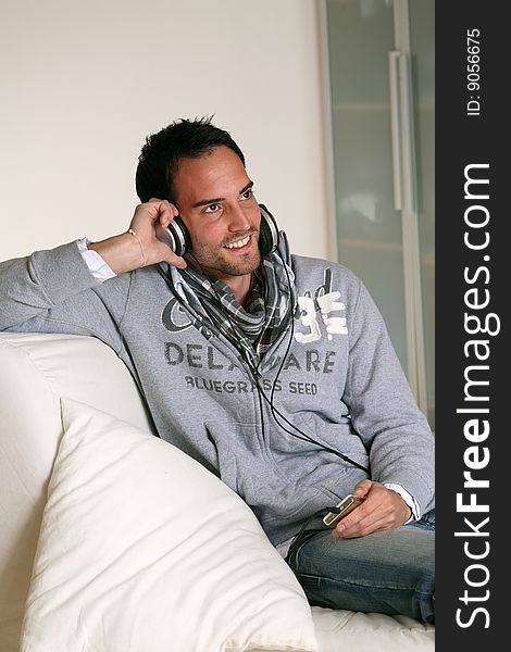 Man with headphones listening to music on an MP3 player and smiling. . Man with headphones listening to music on an MP3 player and smiling.