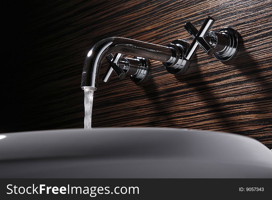 The faucet is watering,wood background.