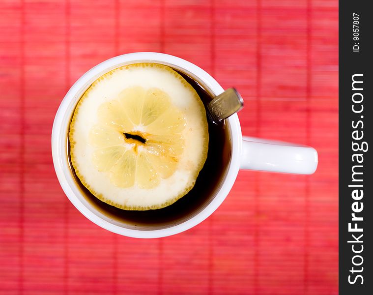 White cup with black tea and piece of lemon