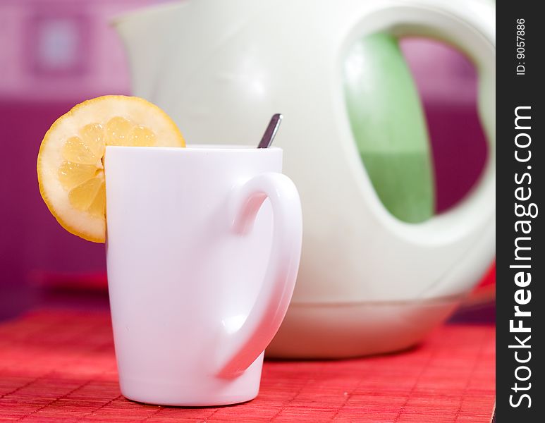 White cup with piece of lemon and kettle. White cup with piece of lemon and kettle