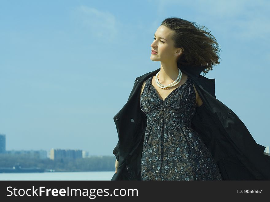 Girl on a background sky, in a developing from wind cloak