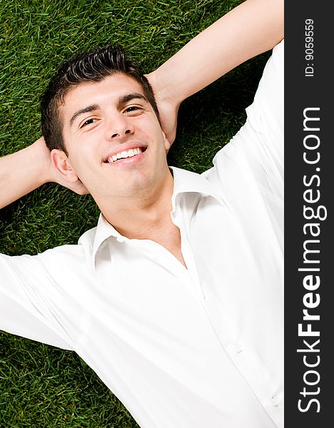 Young handsome man relaxing outdoor lying on back on green grass. Young handsome man relaxing outdoor lying on back on green grass