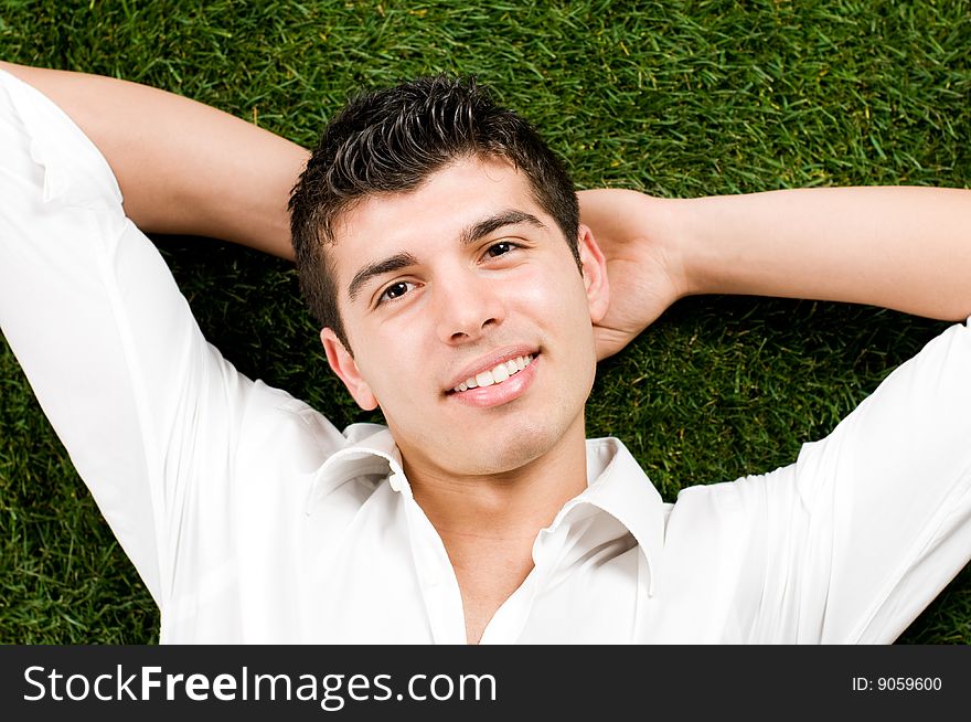Young handsome man relaxing outdoor lying on back on green grass. Young handsome man relaxing outdoor lying on back on green grass