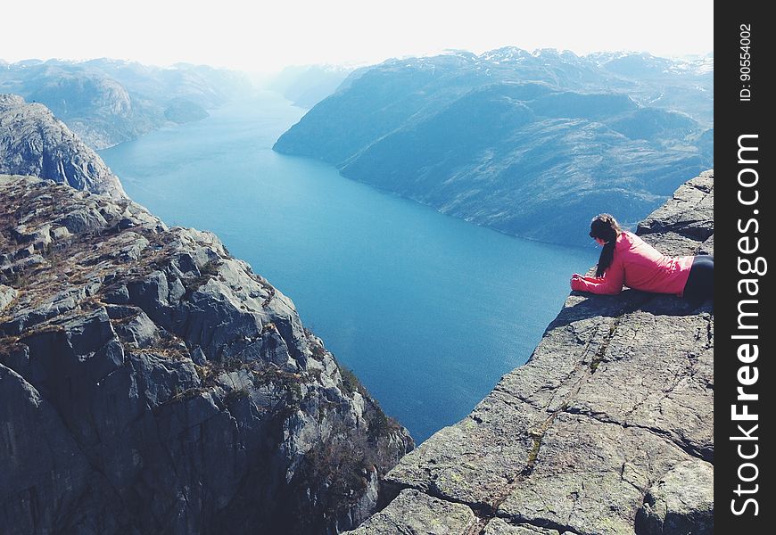 A woman looking down at the fjord at Preikestolen in Norway. A woman looking down at the fjord at Preikestolen in Norway.