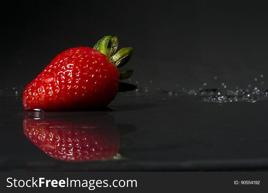 A close up of a red strawberry fruit on dark background.