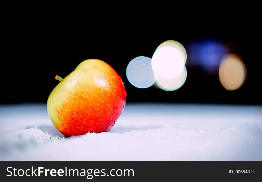 An apple fruit in a pile of snow. An apple fruit in a pile of snow.