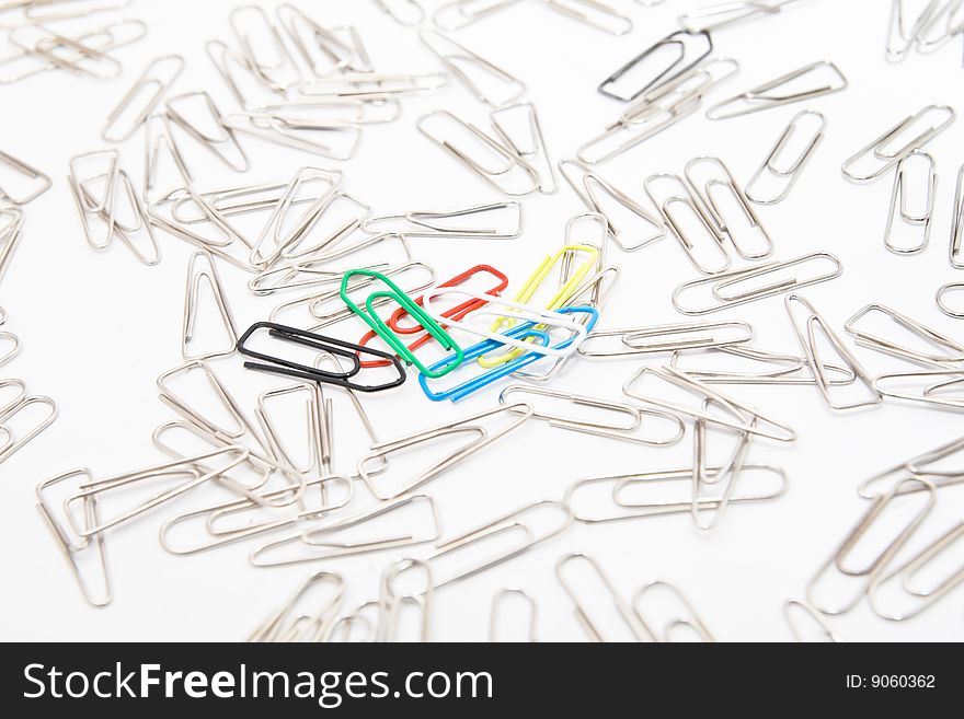 Five colourful paperclips among many steel grey paperclips on white background. Five colourful paperclips among many steel grey paperclips on white background