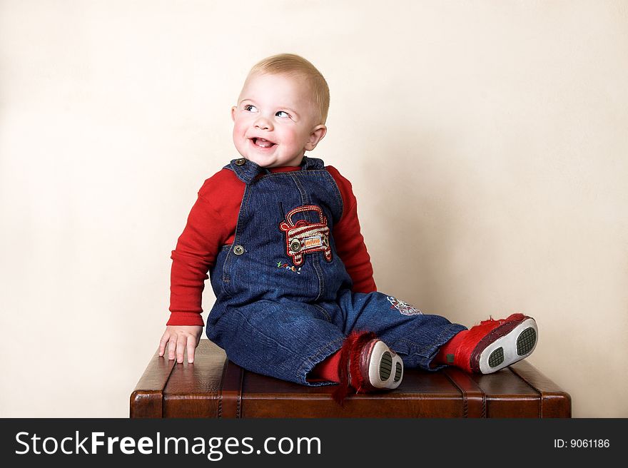 Baby boy sitting on an old style trunk