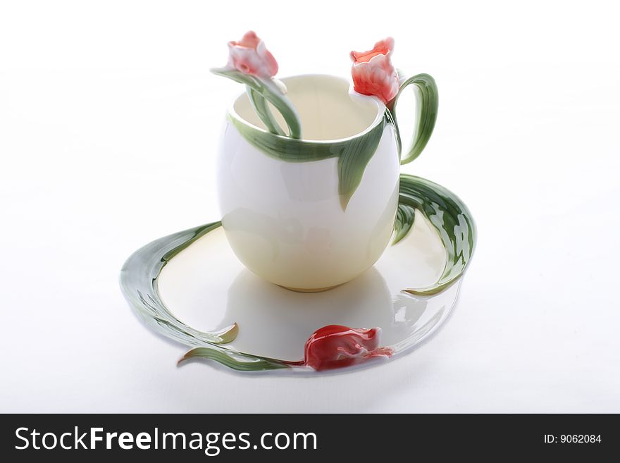 Saucer, cup and spoon decorated with red flower and green color. Saucer, cup and spoon decorated with red flower and green color