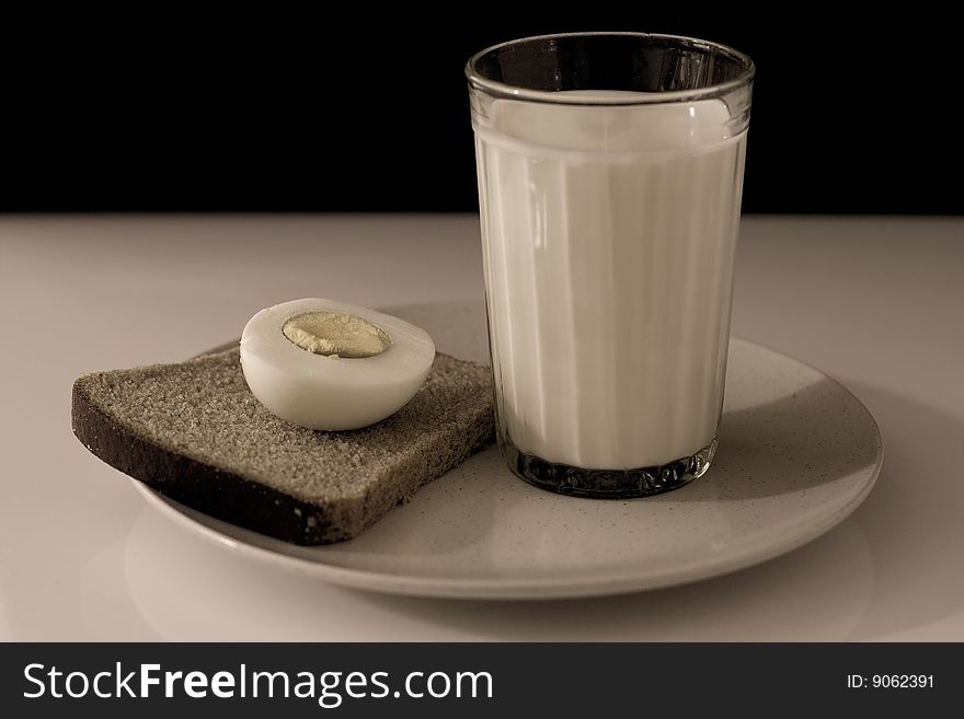 A half egg, a slice of bread, and a glass of milk. A half egg, a slice of bread, and a glass of milk
