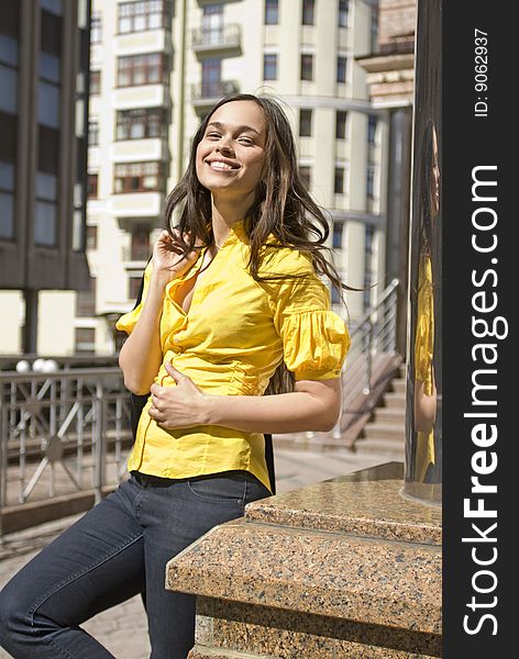 Beautiful happy student in yellow blouse stands on the downtown