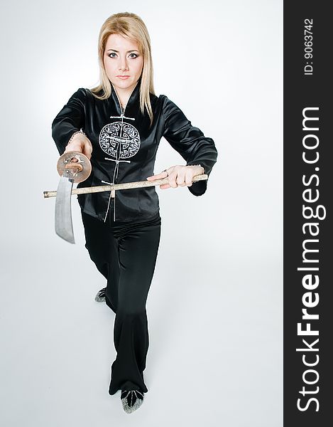 Attractive woman in Japanese shirt with sword, studio shot