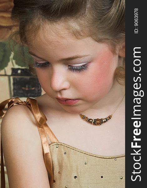 Blond Flower girl wearing a golden dress with beadwork