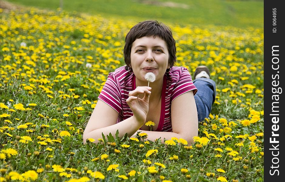 Young woman lying in a meadow full of dandelions