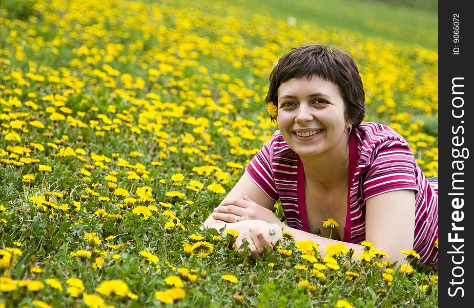 Young woman lying in a meadow full of dandelions