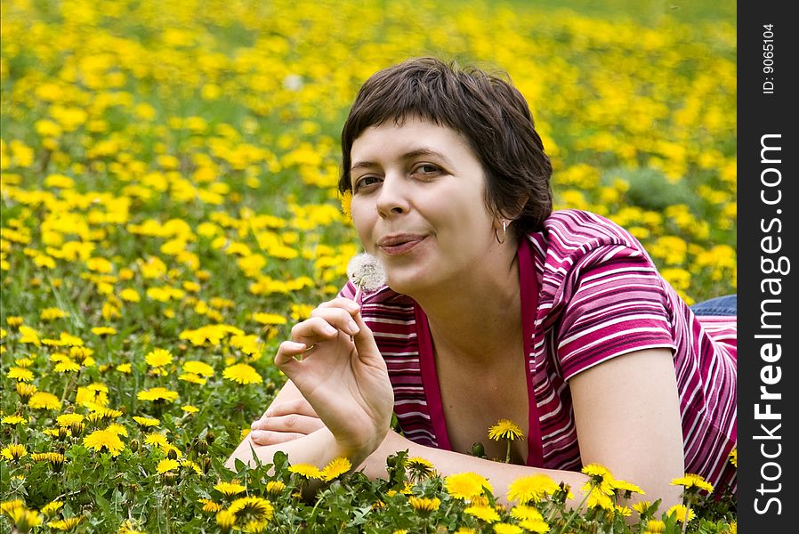 Young woman lying in a meadow full of dandelions