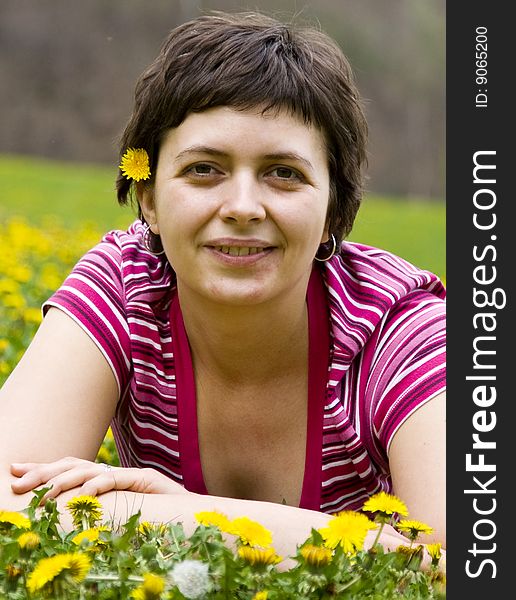 Young woman lying in a meadow full of dandelions