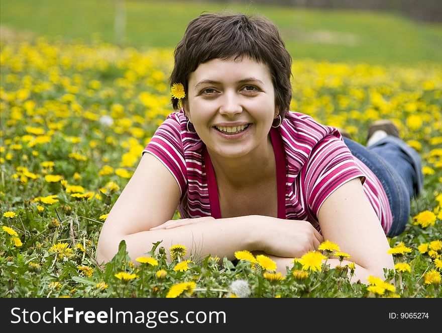 Young woman lying in a meadow full of dandelions