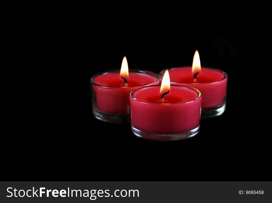 Three lit candles on a black background