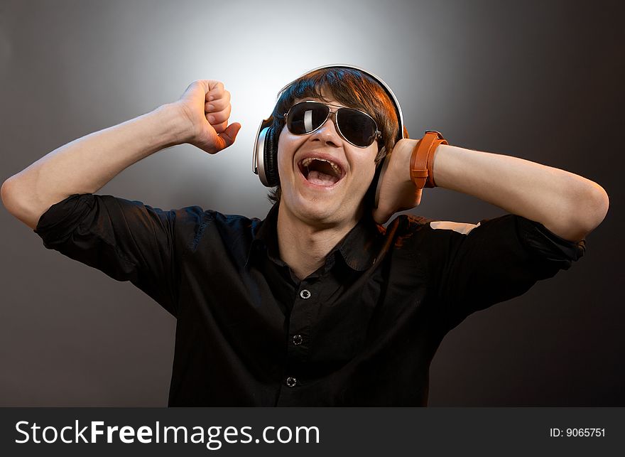 Young screaming caucasian dj with headphones over grey background. Young screaming caucasian dj with headphones over grey background