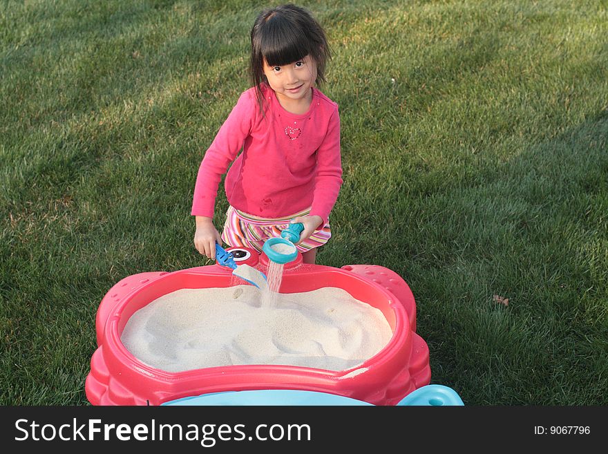 Asian Girl Playing In A Sand Table