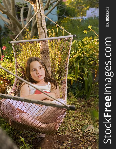 Little girl daydreaming in a hammock in backyard. Little girl daydreaming in a hammock in backyard