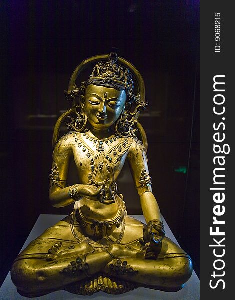 Golden copper buddha statue on black background.