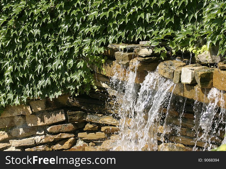 Waterfall between vegetation. Water and stone.