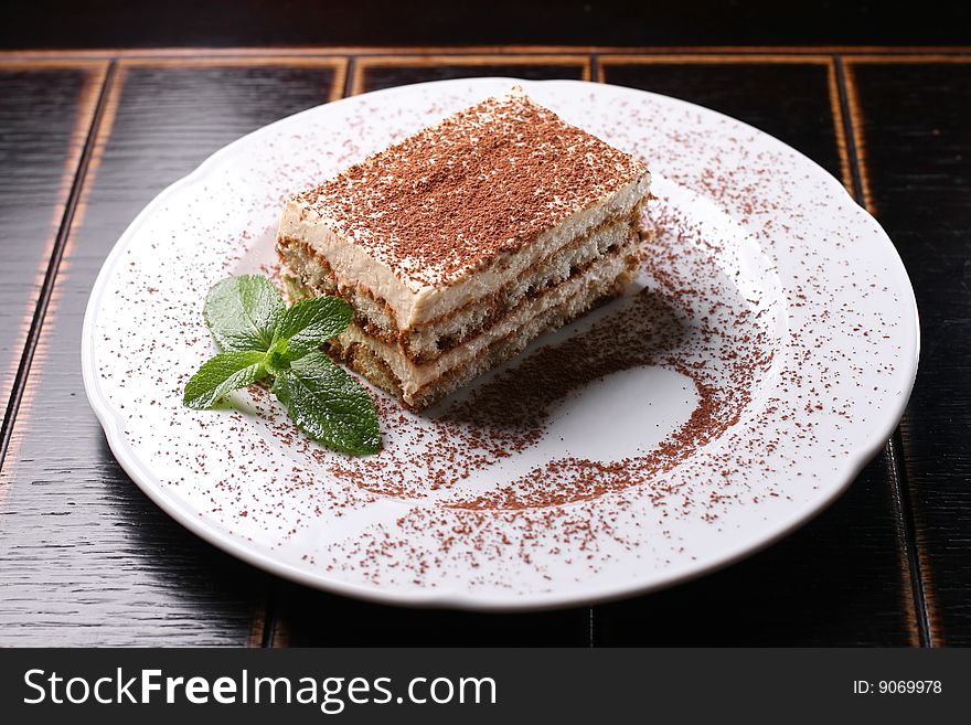 Chocolate cake on a white dish with by a mint. Chocolate cake on a white dish with by a mint