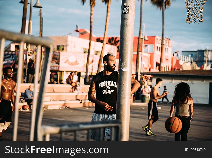 A basketball court on the beach with people.