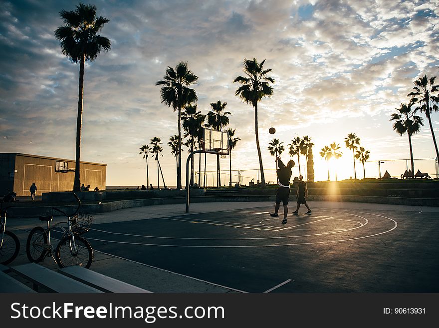 Kids playing basketball on a court at sunset. Kids playing basketball on a court at sunset.