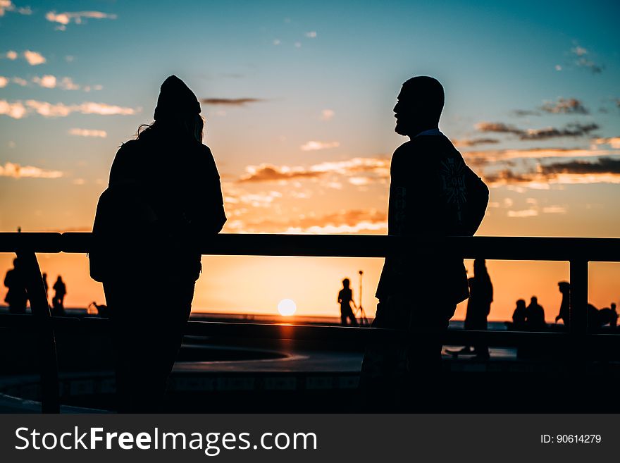 Couple seen in silhouette possibly watching a game of golf at sunset, golden sky and fluffy cloud. Couple seen in silhouette possibly watching a game of golf at sunset, golden sky and fluffy cloud.