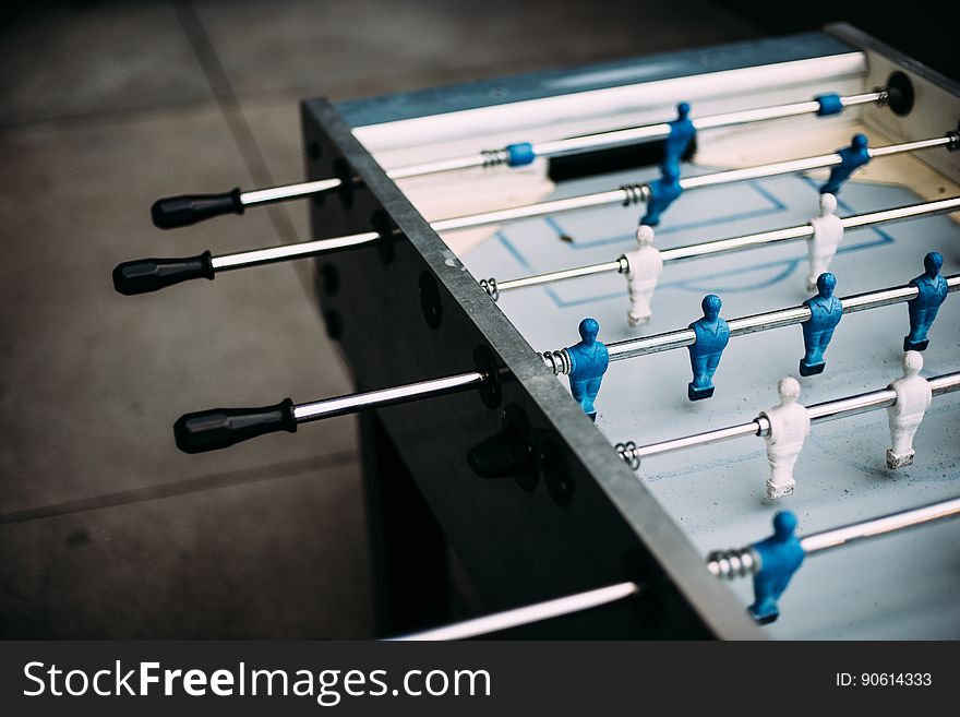 Unoccupied foosball table with blue and white men.