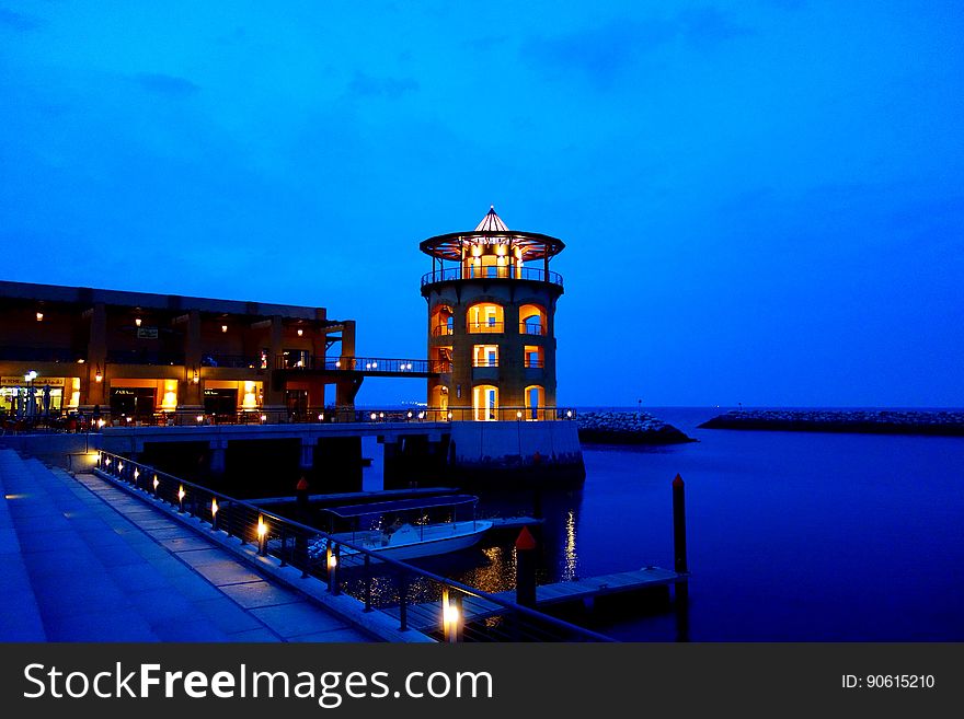 Ocean pier and docks illuminated at night with round tower and blue tone. Ocean pier and docks illuminated at night with round tower and blue tone.