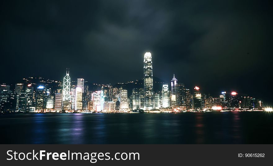Illuminated modern city skyline viewed from sea at night.