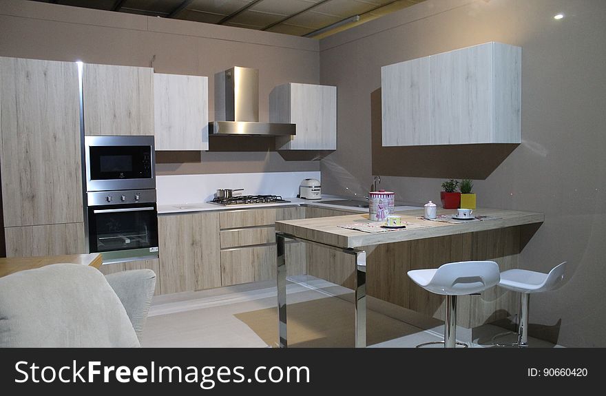 Modern kitchen diner in small flat or apartment, with sink, microwave, oven, cooker, table and chairs, cupboard, extractor fan, hood, looking clean and smart. Modern kitchen diner in small flat or apartment, with sink, microwave, oven, cooker, table and chairs, cupboard, extractor fan, hood, looking clean and smart.