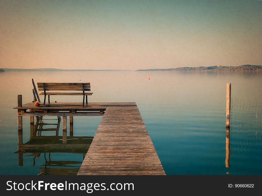 Wooden bench on dock along waterfront as sunset. Wooden bench on dock along waterfront as sunset.