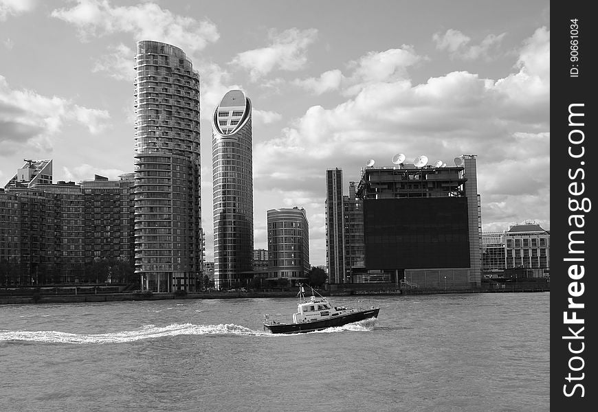 Boat in river passing urban waterfront skyline with skyscrapers in black and white. Boat in river passing urban waterfront skyline with skyscrapers in black and white.