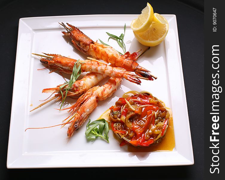 Shrimps on a grill with vegetables and lemon.