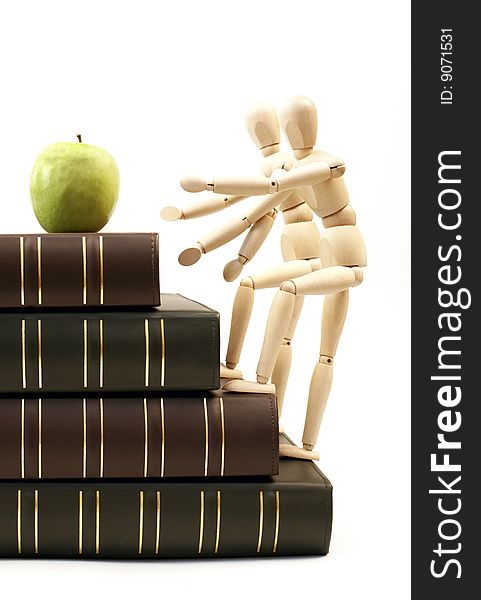 Wooden figurine on a stack of books going up for an apple