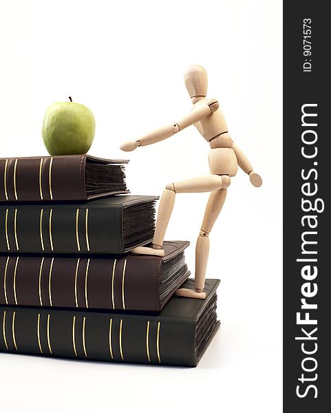 Wooden figure on a stack of books going up for an apple