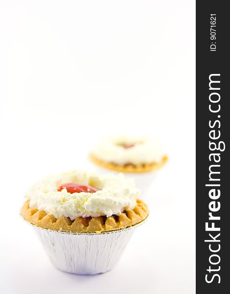 Two strawberry tarts with cream on a white background