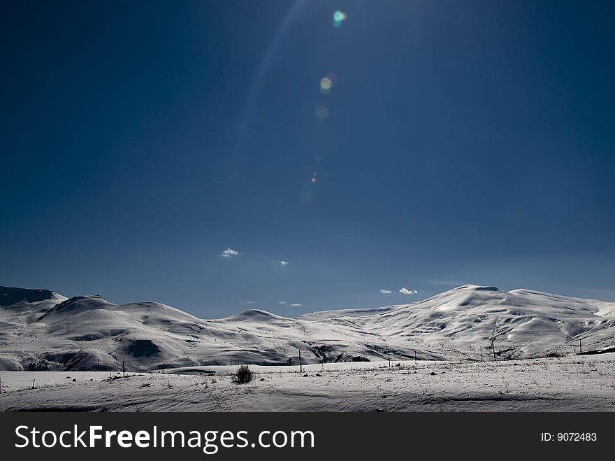 Snowcapped mountain range with lens flare. Snowcapped mountain range with lens flare.