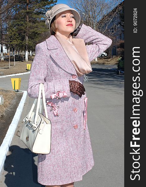 Stylish young woman - lady in coat and lady's hat with handbag (purse) on the street. Stylish young woman - lady in coat and lady's hat with handbag (purse) on the street.