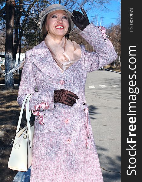 Stylish young woman - lady in coat and lady's hat with handbag (purse) on the street. Stylish young woman - lady in coat and lady's hat with handbag (purse) on the street.