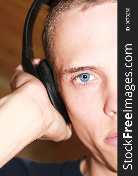 Male with blue eyes looking at you and listening to his headphones. Male with blue eyes looking at you and listening to his headphones