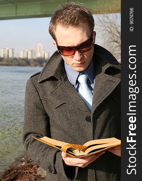 Businessman reading book outdoor by the river