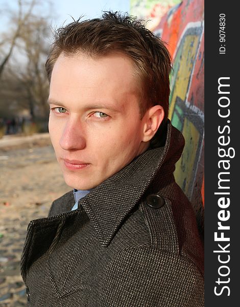 Male portrait outdoor, standing at the wall