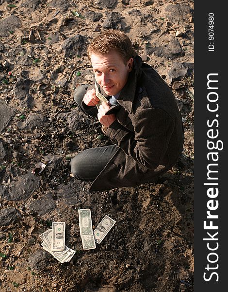 Happy businessman counting his money on the ground. Happy businessman counting his money on the ground