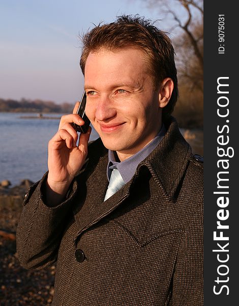 Happy businessman on mobile phone outdoor by the river. Happy businessman on mobile phone outdoor by the river